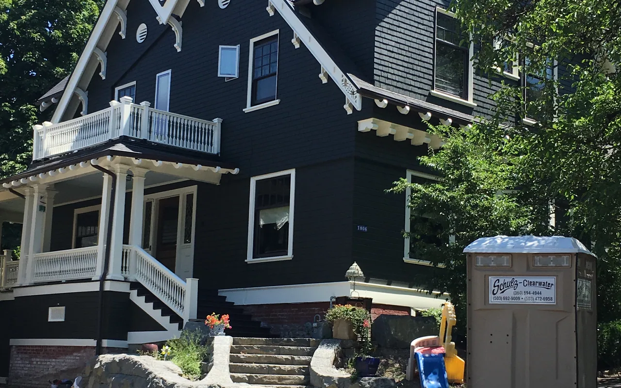 Dark Portland Victorian with white porch rails, balcony and gable trim