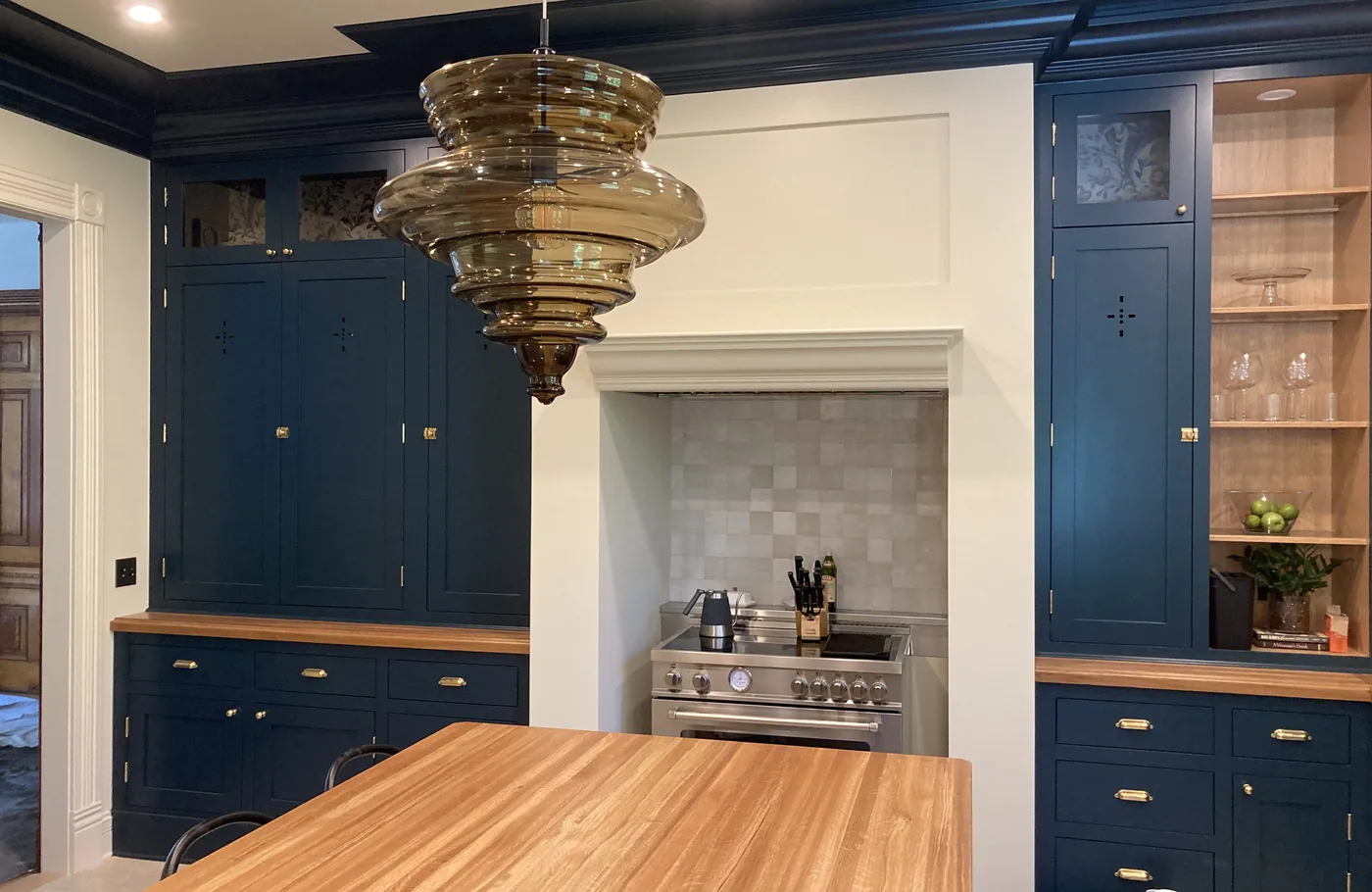Navy painted kitchen cabinets around a butcher-block island