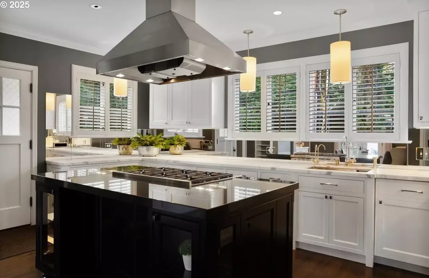 White cabinets around a black island and range hood