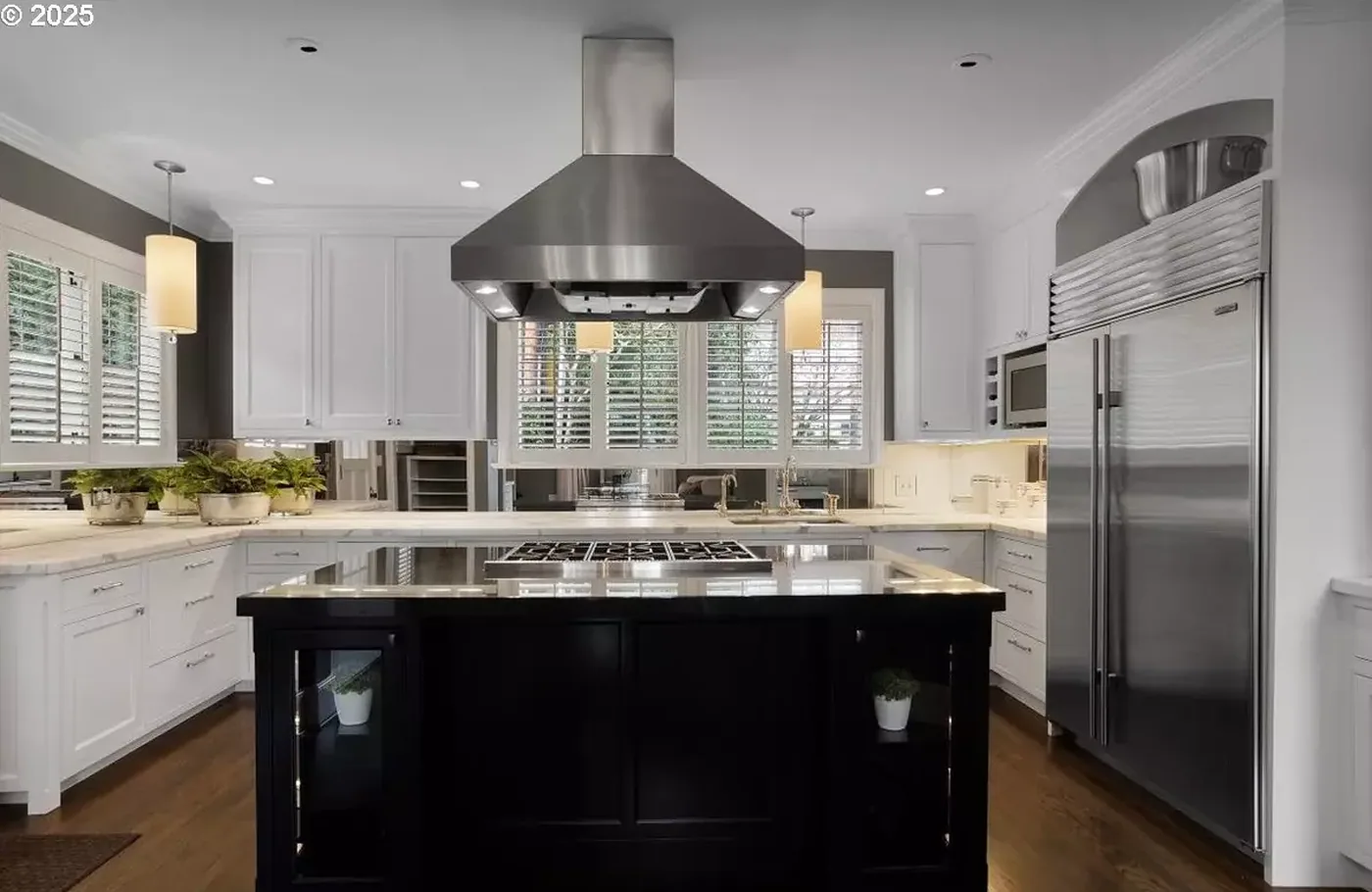 Painted cabinets and black island under a steel hood