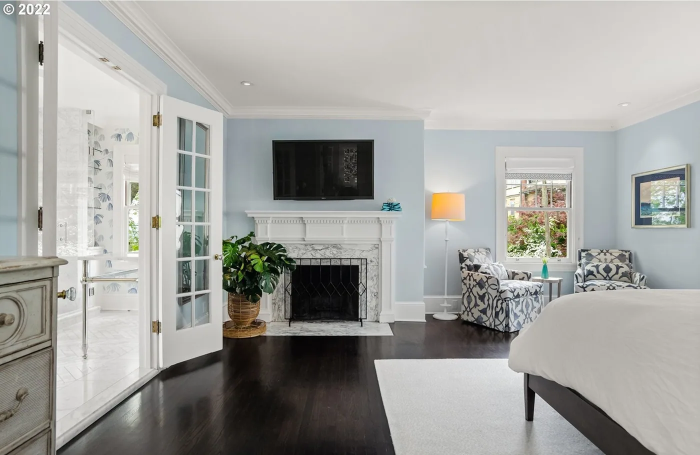Bedroom with pale blue walls and a white fireplace
