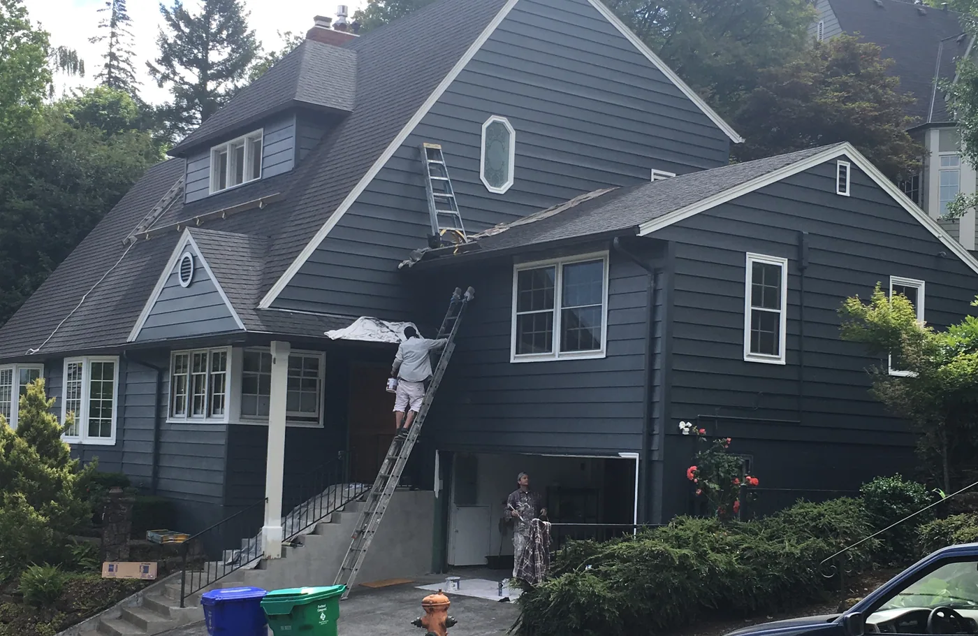 Dark blue siding and white trim going on a Portland home, painters on ladders