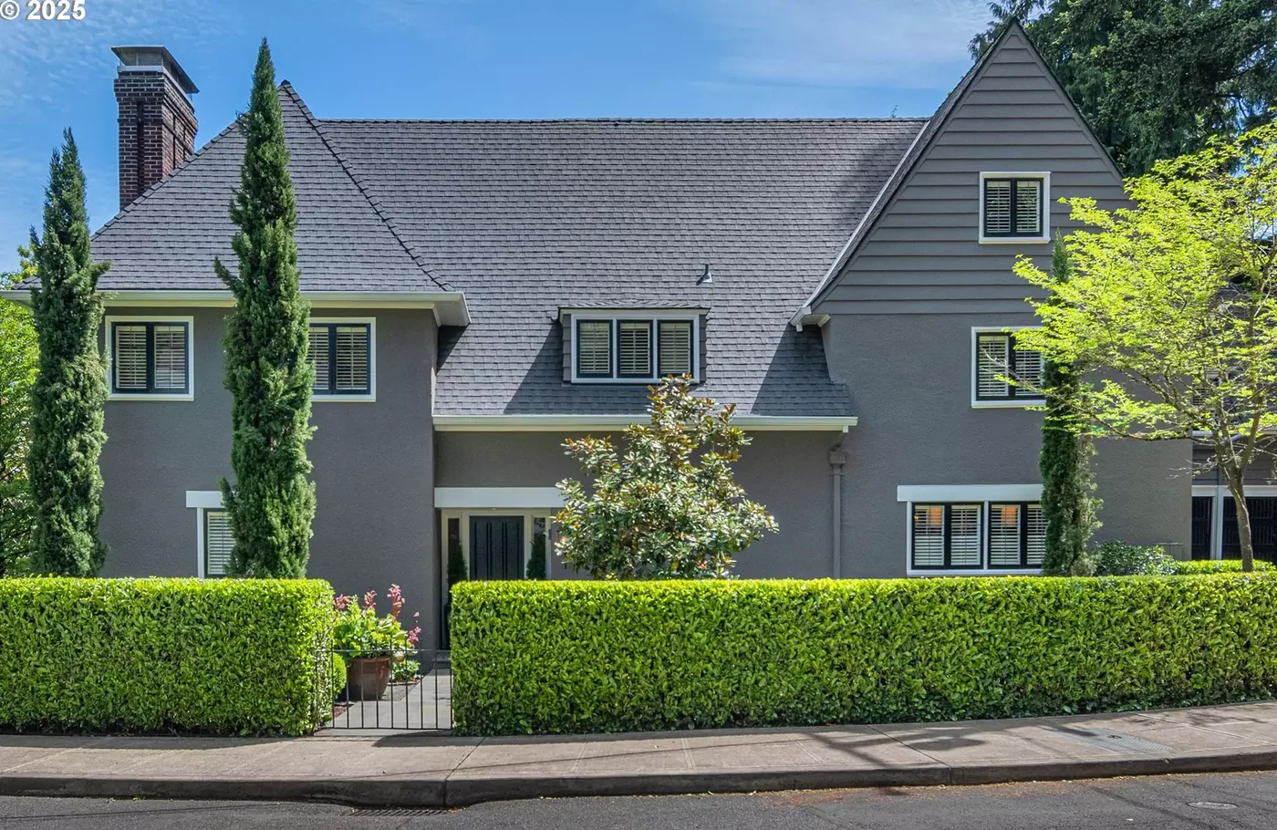 Grey Tudor home behind a clipped hedge