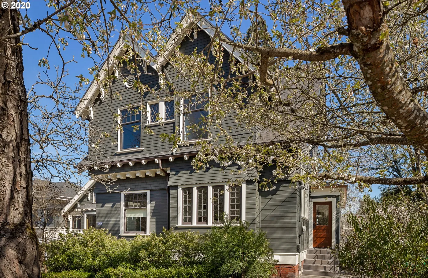 Grey craftsman home under bare spring trees