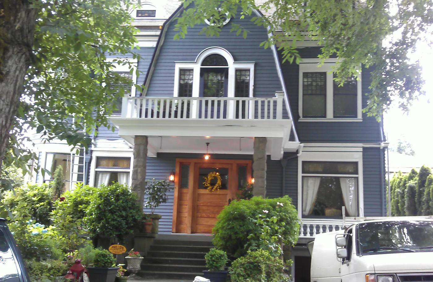 Grey-blue gambrel home with white trim and a stained front door