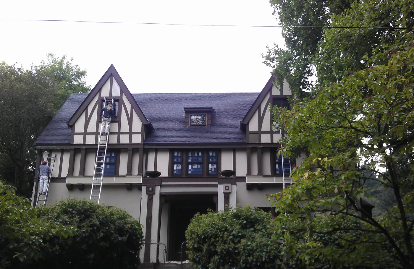 Tudor-style home with dark half-timbering during an exterior repaint