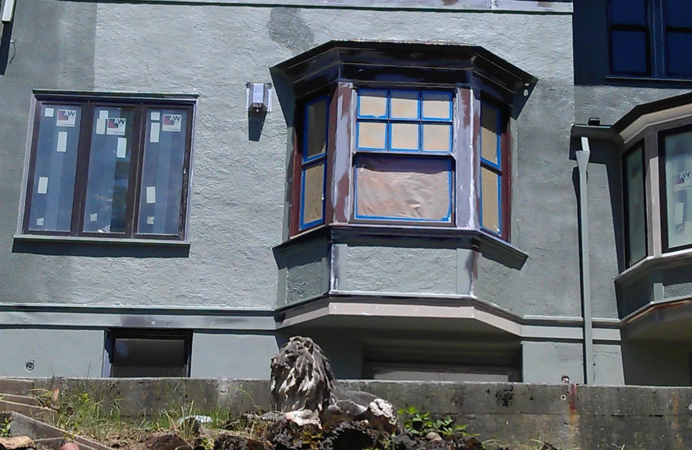 Painted bay windows and trim on a grey stucco building