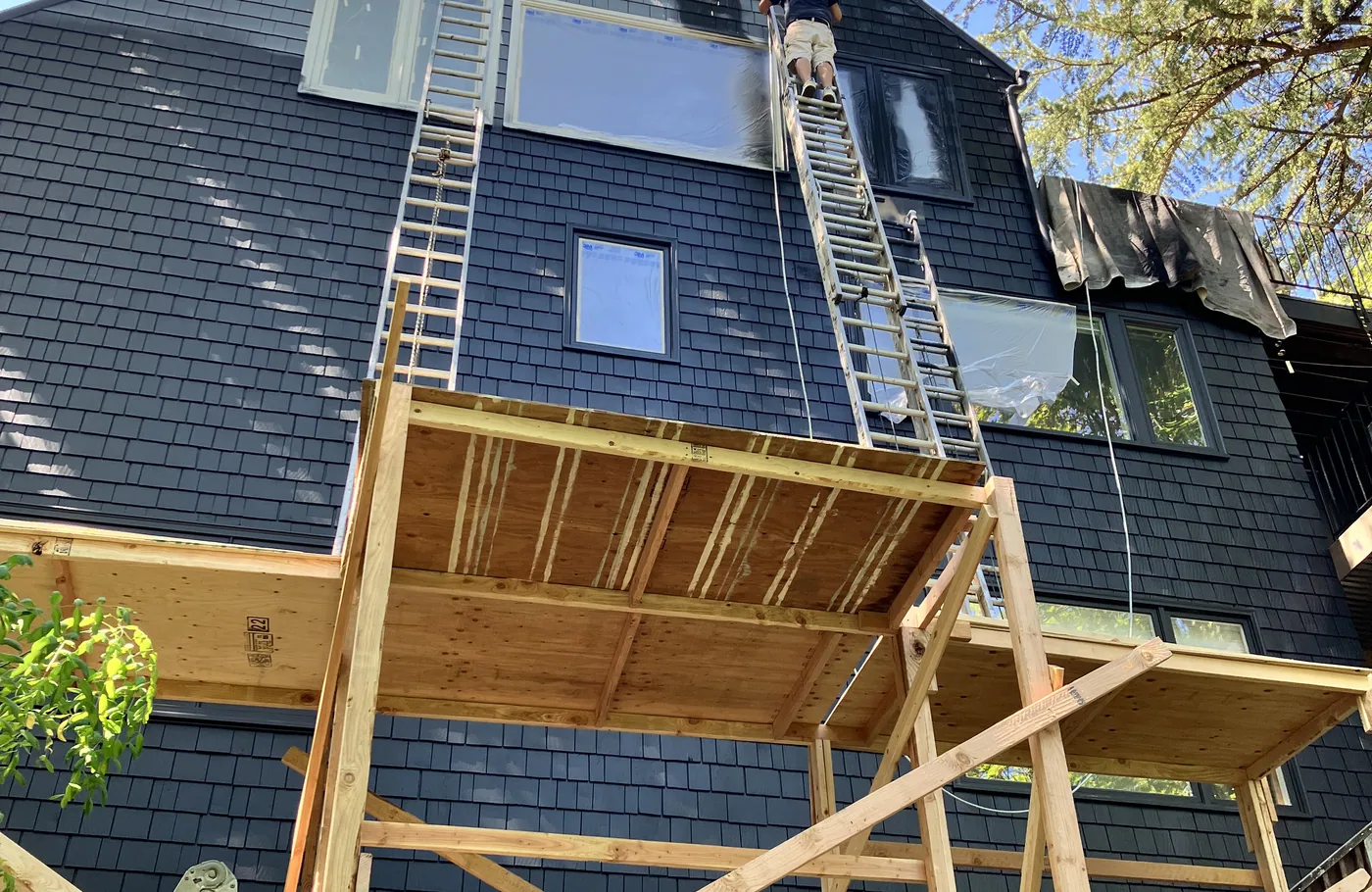 Scaffolding up on a tall dark-sided home for an exterior repaint