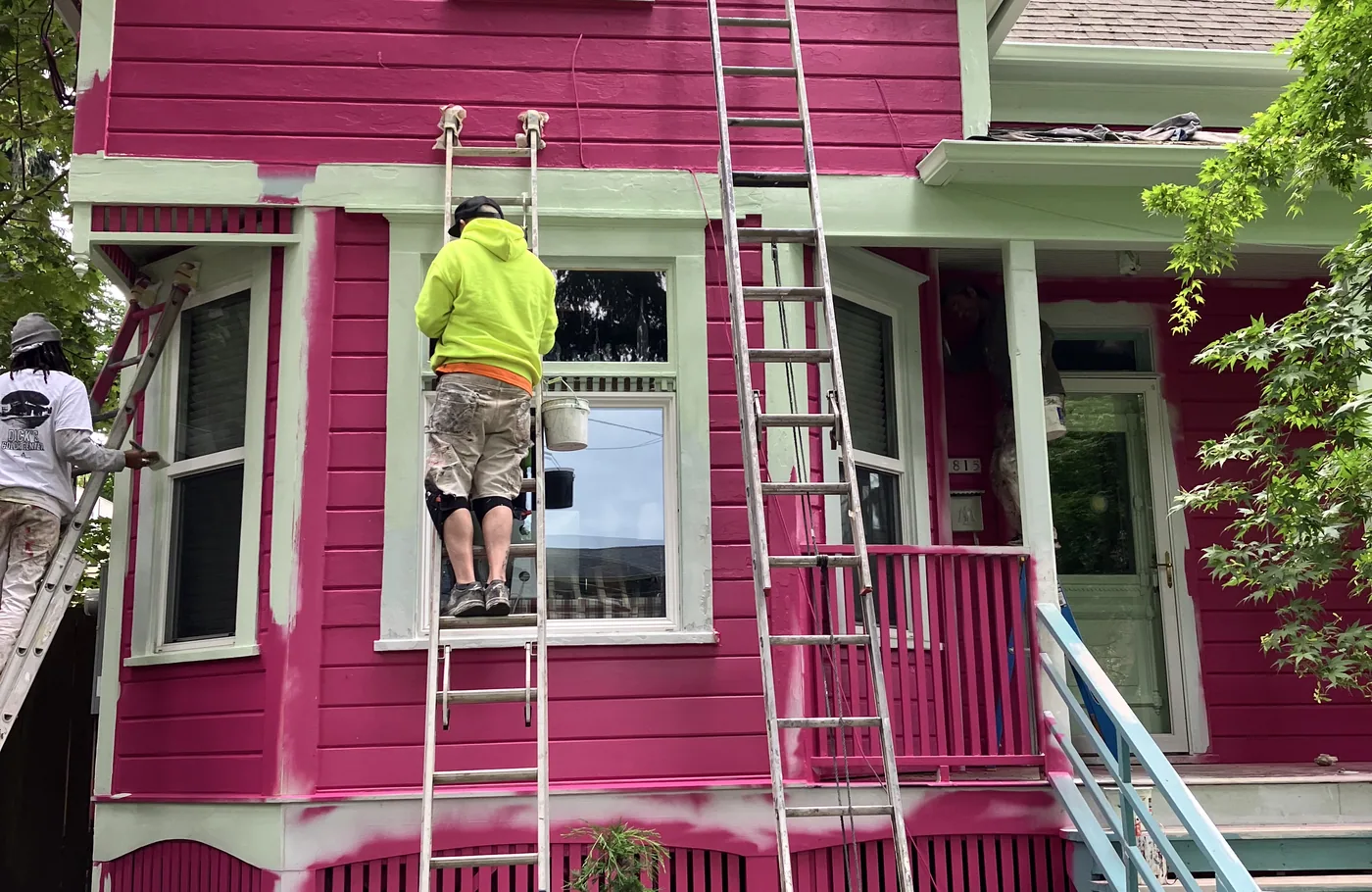 Painters on ladders applying magenta to a Portland Victorian
