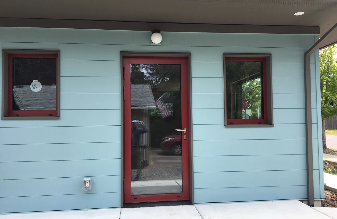 Blue siding with a red door and red window trim on a new build