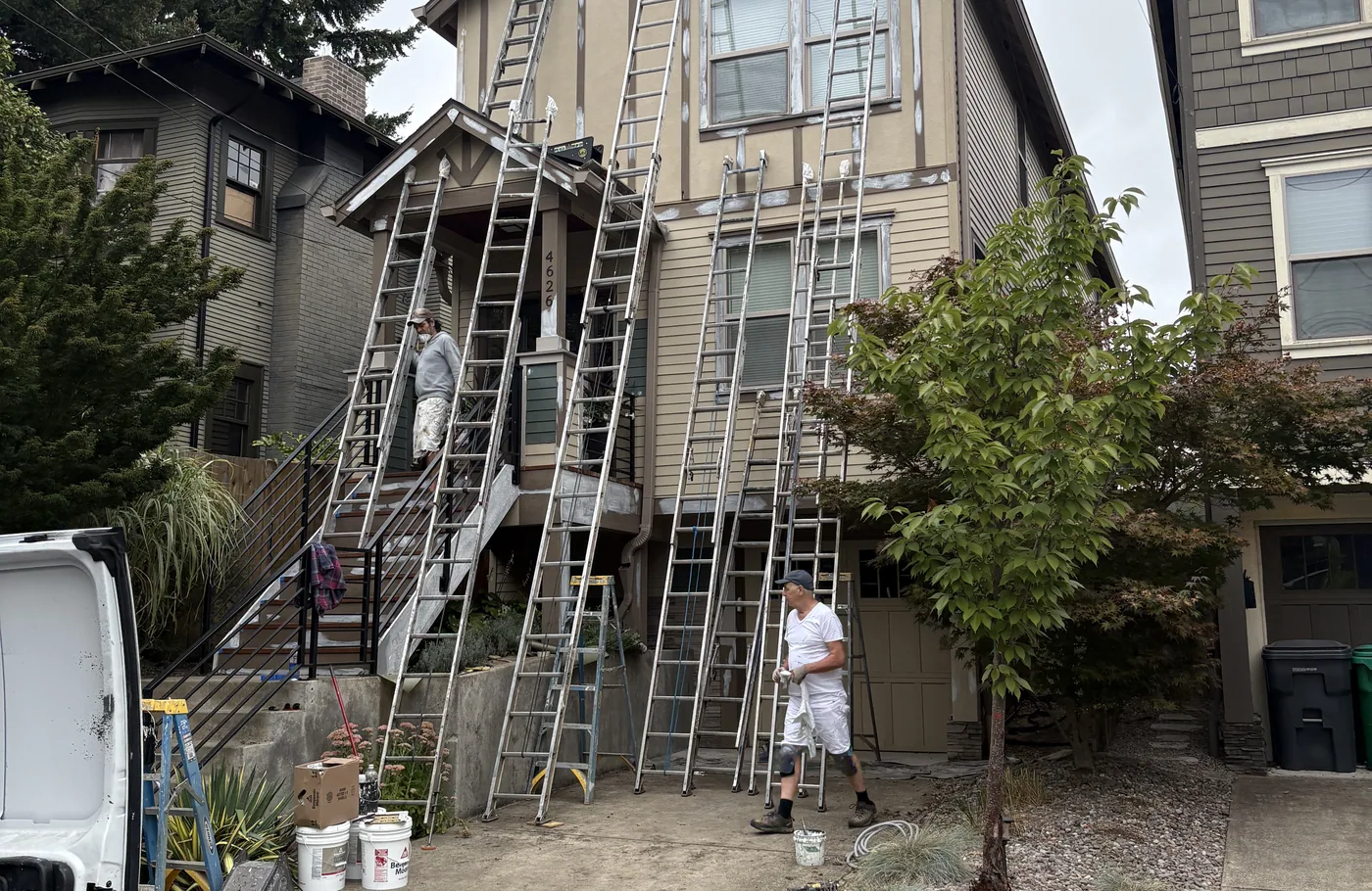 Ladders set up across a tall Portland home mid-repaint
