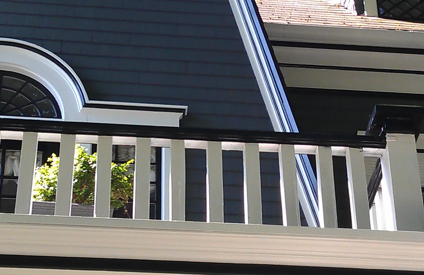 Painted balcony rail and arched window trim on a Portland home