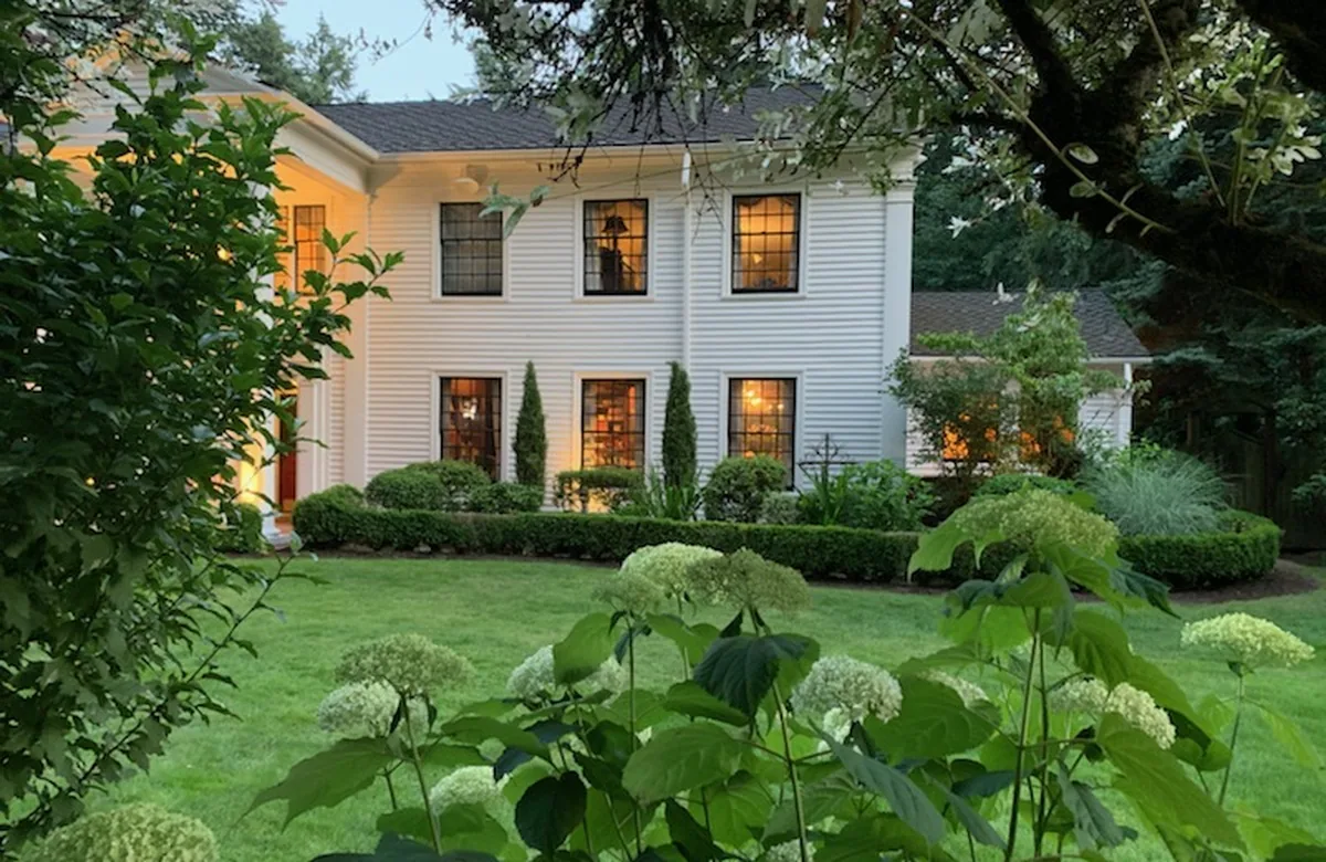 White Portland home with fresh trim behind a garden lawn